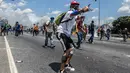 Demonstran menggunakan ketapel saat demonstrasi menentang Presiden Nicolas Maduro di Caracas,  Venezuela, Rabu (26/4). Hingga kini, bentrokan antara demonstran dan polisi telah menyebabkan 26 orang tewas. (AFP PHOTO) 