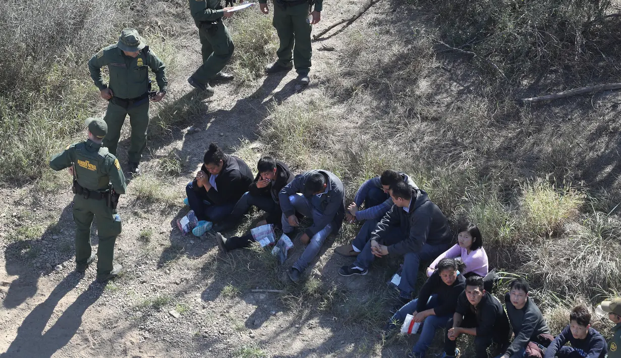 Petugas menangkap imigran Meksiko yang berusaha menyeberangi perbatasan AS-Meksiko di McAllen, Texas (3/1). Ribuan imigran masuk secara ilegal melintasi perbatasan mencari suaka di AS jelang pelantikan AS Donald Trump. (AFP Photo/John Moore/Getty Images)