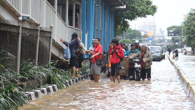 Warga melintasi genangan banjir di Jalan Gunung Sahari Jakarta, Selasa (25/2/2020). Hujan yang mengguyur Jakarta sejak Senin (24/2) malam membuat sejumlah kali meluap dan menyebabkan banjir. (Liputan6.com/Helmi Fithriansyah)