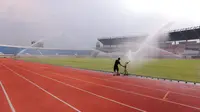 Seorang pekerja menyiram rumput Stadion Si Jalak Harupat (SJH), Bandung, Sabtu (21/10/2023). (Bola.com/Bagaskara Lazuardi)