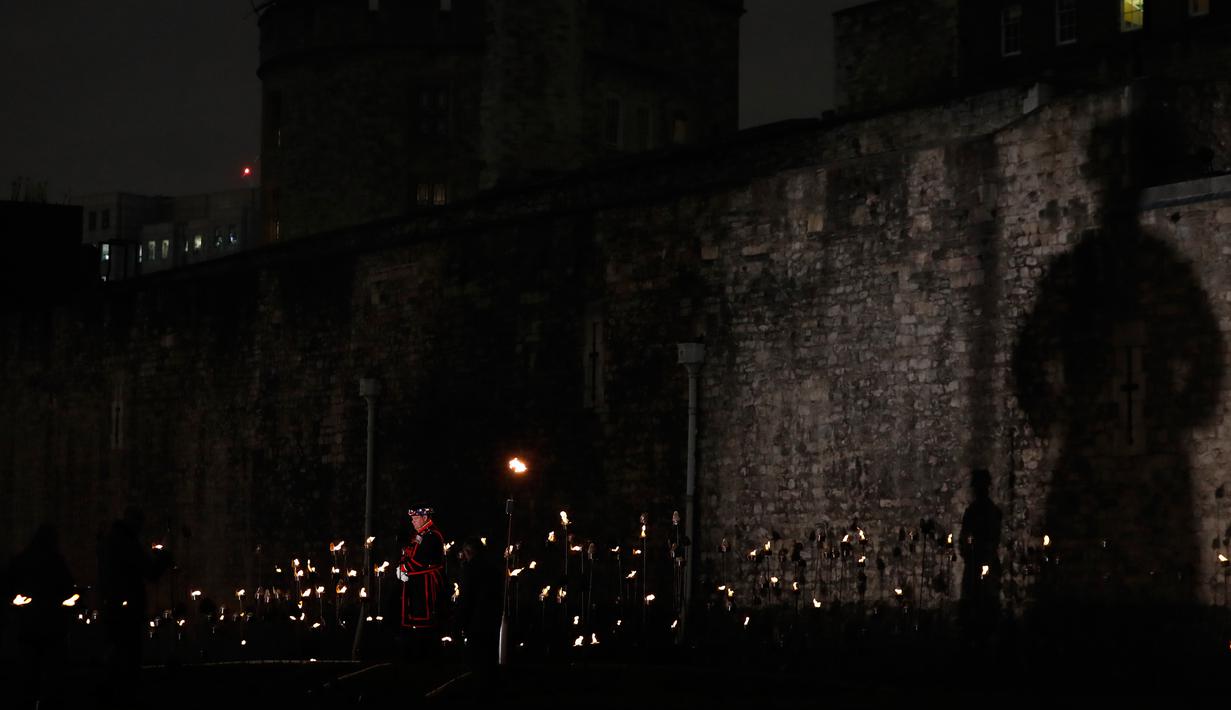 Yeoman Warders atau 'Beefeaters' berdiri di antara ribuan lilin di parit kering Tower of London, Inggris, Selasa (6/11). Lilin itu untuk menandai 100 tahun akhir Perang Dunia I. (AP Photo/Alastair Grant)