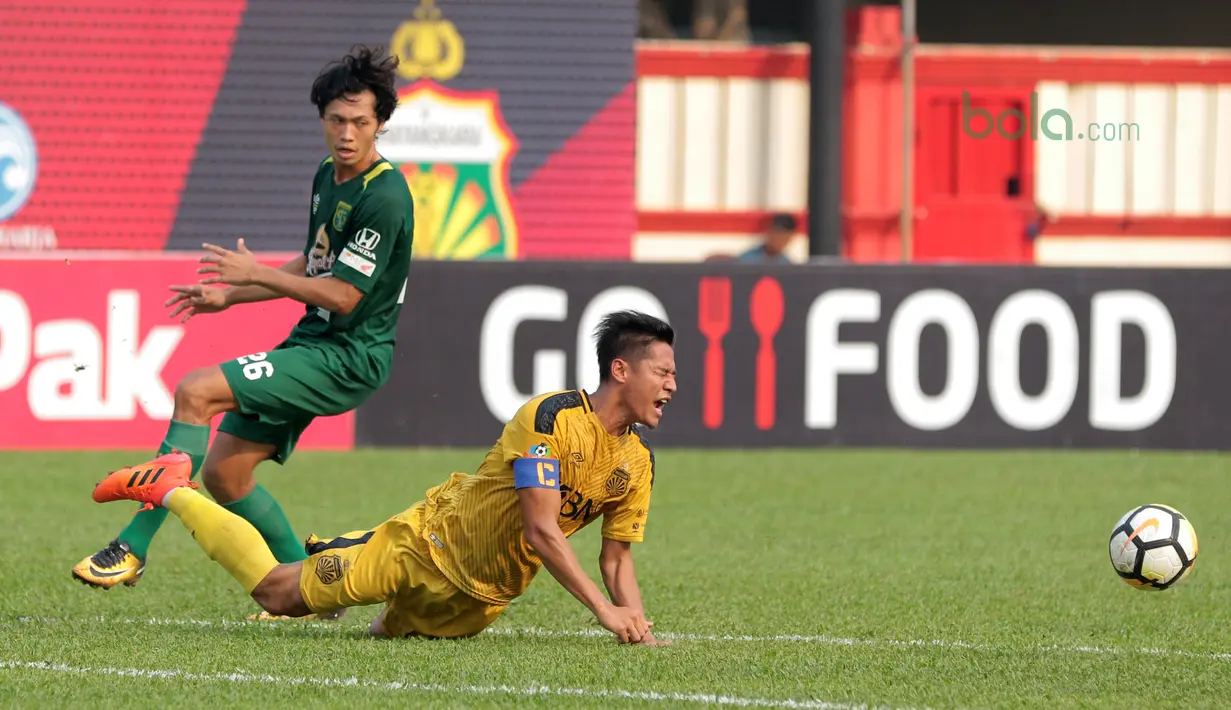 Indra Kahfi jatuh saat berebut bola dengan pemain Persebaya Surabaya, Rishadi Fauzi pada laga Gojek Liga 1 bersama Bukalapak di Stadion PTIK, Jakarta, Rabu (11/7/2018). Bhayangkara bermain imbang 3-3. (Bola.com/Nick Hanoatubun)