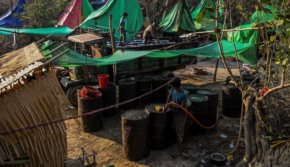 Pekerja mengisi sejumlah drum dengan minyak mentah saat melakukan pengeboran di sumur minyak ilegal di Minhla, Myanmar, 10 Maret 2019. Para pekerja dapat memperoleh hingga 600 barel minyak per hari. (Ye Aung THU/AFP)