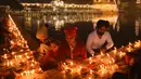 Umat Sikh menyalakan lampu tanah di Kuil Emas yang diterangi pada peringatan kelahiran Guru Nanak di Amritsar, India, 19 November 2021. Guru Nanak adalah Guru Sikh pertama dan pendiri Sikhisme. (AP Photo/Prabhjot Gill)