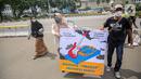 Sejumlah orang yang tergabung dalam KOMPAK menggelar aksi #ParadeMural membawa poster di kawasan Patung Arjuna Wijaya, Jakarta, Rabu (17/11/2021). Aksi tersebut untuk mendesak Presiden untuk mengesahkan Revisi PP 109/2012. (Liputan6.com/Faizal Fanani)