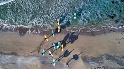 Peserta kursus selancar memasuki air saat menantang hawa dingin di Lofoten Islands, Norwegia, (10/3/2018). Suhu udara minus 13°C dan suhu diatas air sekitar 4°C. (AFP/Oliver Morin)