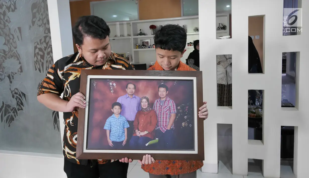 Muhammad Ivanka Rizaldi Nugroho (kiri) dan Muhammad Aufa Wikantyasa Nugroho (kanan) anak dari Kepala Pusat Data Informasi dan Humas BNPB Sutopo Purwo Nugroho melihat  foto keluarga di rumah duka Raffles Hils, Cimanggis,  Depok, Jawa Barat, Minggu (7/7/2019). (Liputan6.com/Herman Zakharia)