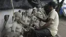 Perajin membuat patung Dewa Ganesha di sebuah bengkel di pinggiran Hyderabad, India, Rabu (18/8/2021). ​Patung ramah lingkungan yang dibuat jelang perayaan Ganesh Chaturthi tersebut dibuat dari lumpur, serat rami, dan bambu untuk mengurangi polusi air. (NOAH SEELAM/AFP)