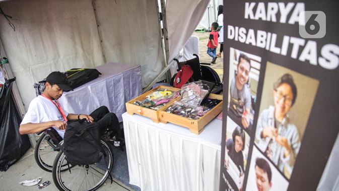 Penyandang disabilitas menjaga booth pada acara puncak peringatan Hari Disabilitas Internasional 2019 di Plaza Barat Gelora Bung Karno, Jakarta, Selasa (3/12/2019). Acara ini mengangkat tema 'Indonesia Inklusi, Disabilitas Unggul'. (Liputan6.com/Faizal Fanani)