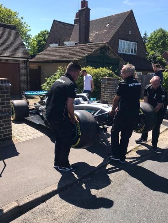 Sejumlah orang mengangkat mobil F1 dari Lewis Hamilton untuk bocah penderita kanker tulang langka Harry Shaw di Redhill, Surrey, Inggris, 13 Mei 2019. Setelah memenangi balapan F1 GP Spanyol, Lewis Hamilton mendedikasikan kemenangan yang diraihnya untuk Harry. (James Shaw/via REUTERS)