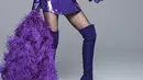 Di foto ini, Anne Hathaway mengenakan busana serba ungu. Mini blazer dress berwarna ungu dipadu dengan stocking hitam yang dilayer dengan high boots ungu, dan ia tampak membawa aksesori berupa bulu yang juga berwarna ungu. Foto: Instagram.