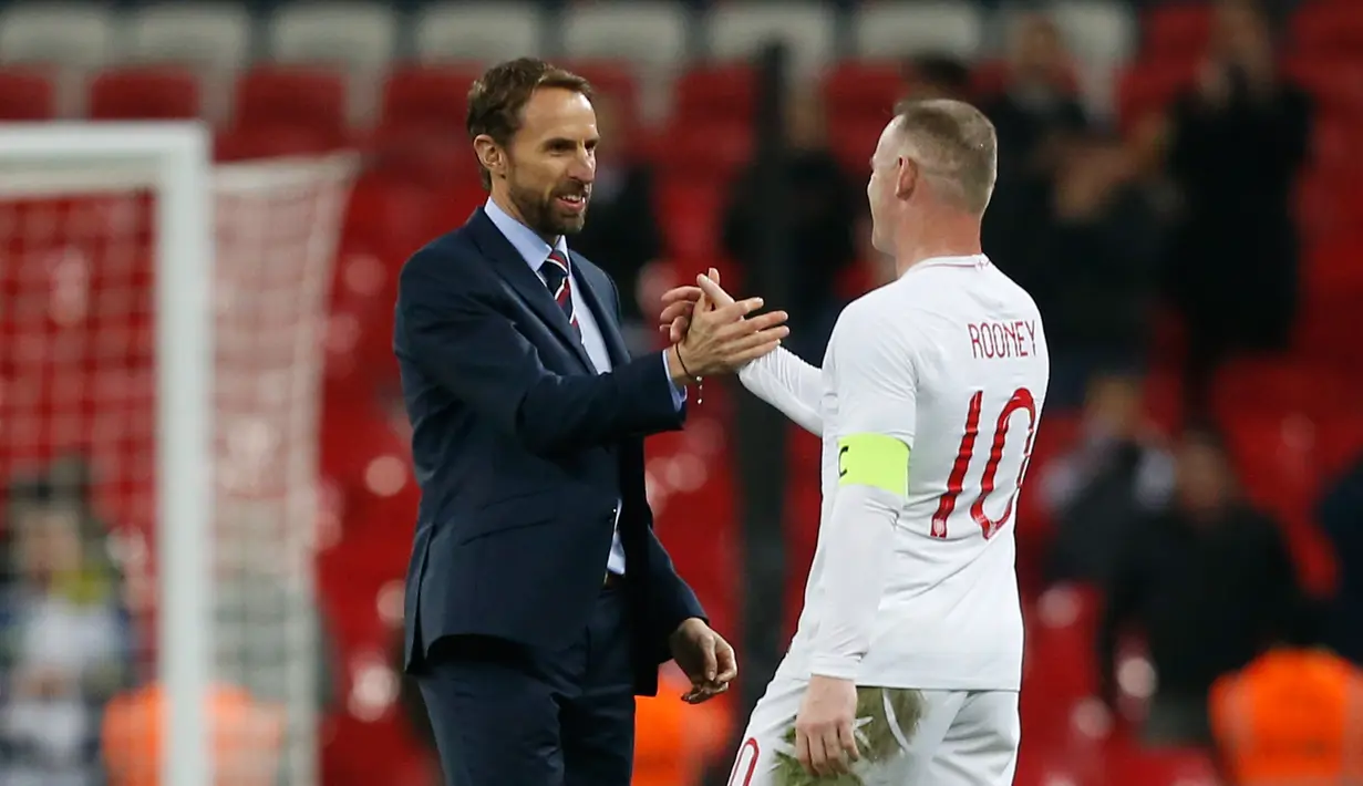 Usai pertandingan, Wayne Rooney bersalaman dengan sang pelatih Gareth Southgate pada laga persabahatan kontra Amerika Serikat yang berlangsung di Stadion Wembley, Inggris. Timnas Inggris menang 3-0. (AFP/Ian Kington)