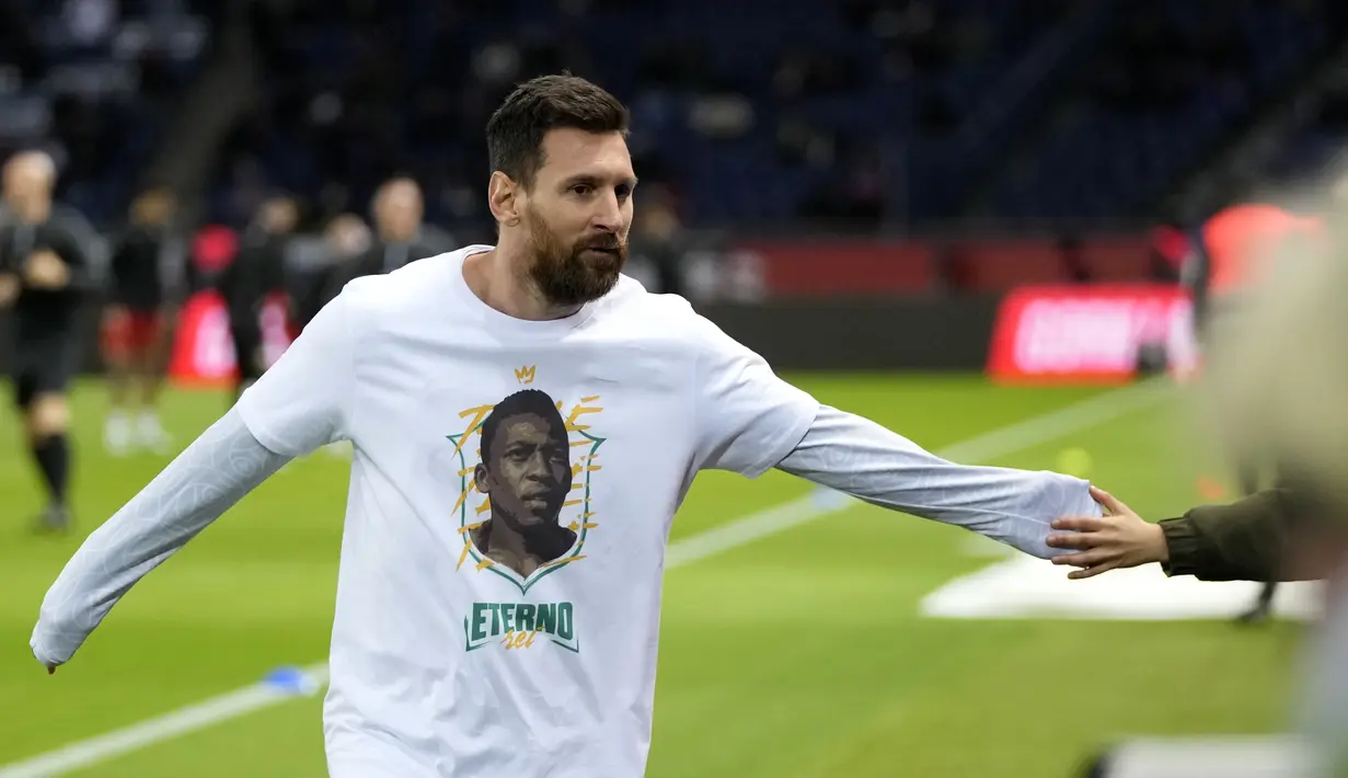 Penyerang Paris Saint-Germain (PSG) Lionel Messi mengenakan kaos dengan potret mendiang legenda sepak bola Brasil Pele sebelum lanjutan Liga Prancis 2022/2023 melawan Angers di Parc des Princes, Kamis (12/1/2023) dini hari WIB. Sebagaimana diketahui, Pele meninggal dunia pada akhir Desember 2022 lalu di usianya yang ke-82 tahun. (AP Photo/Francois Mori)