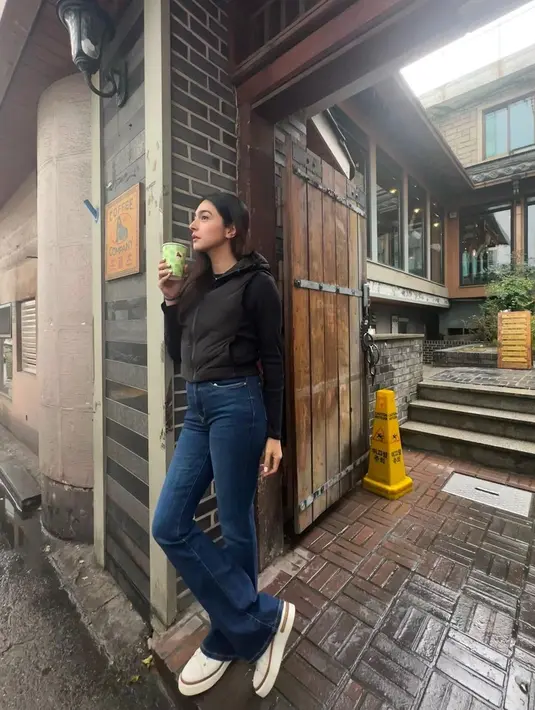 Nabila Syakieb tampil cantik dengan atasan hitam lengan panjang, ditumpuk puffer vest berhoodie yang juga berwarna hitam. Padu padan dengan celana jeans dan sneakers putih membuat Nabila Syakieb terlihat langsing dan tinggi. [Foto: Instagram/nsyakieb85]