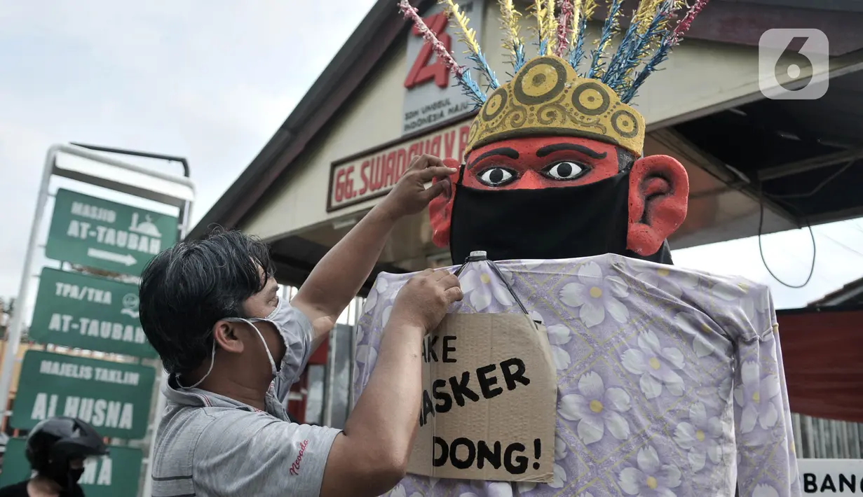 Warga memasangkan masker pada ondel-ondel di depan pintu masuk permukiman RT 12 RW 14, Cipinang Besar Utara, Jakarta, Kamis (16/4/2020). Warga secara swadaya membuat ondel-ondel tersebut sebagai upaya mengajak masyarakat melindungi diri dari penyebaran Covid-19. (merdeka.com/Iqbal S. Nugroho)