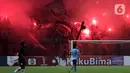 Suporter menyalakan flare saat menyaksikan laga Persija melawan Sabah FC pada laga uji coba internasional di Stadion Patriot Candrabhaga, Kota Bekasi, Minggu (5/6/2022). Pertandingan sepakbola kembali bisa disaksikan secara langsung setelah pemerintah melonggarkan aturan pemakaian masker di luar ruangan. (Liputan6.com/Helmi Fithriansyah)