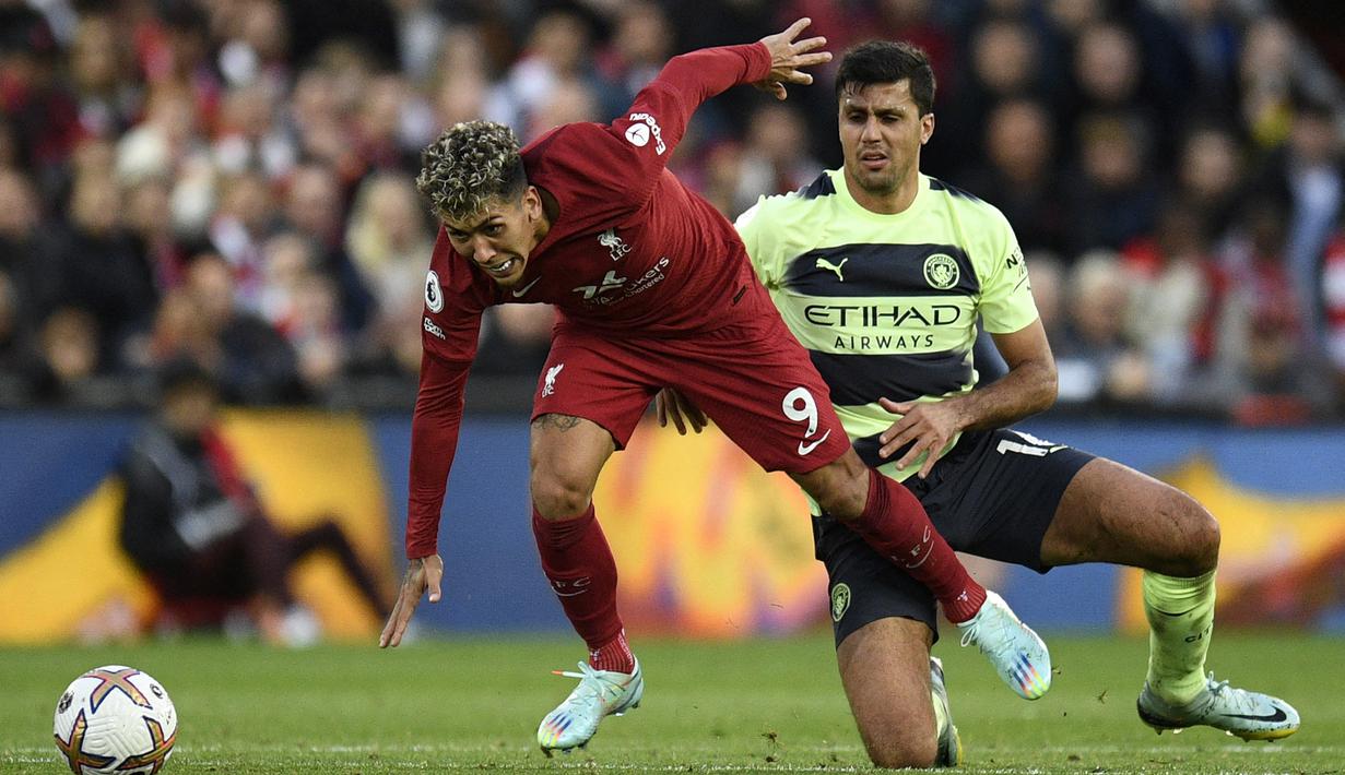 Striker Liverpool, Roberto Firmino berusaha melewati gelandang Manchester City, Rodri pada laga Liga Inggris 2022/2023 di Anfield Stadium, Liverpool (16/10/2022). Roberto Firmino yang telah dipastikan akan cabut dari Liverpool akhir musim ini usai menolak perpanjangan kontrak kabarnya tengah diincar oleh Al Nassr FC untuk diduetkan dengan Cristiano Ronaldo. (AFP/Oli Scarff)