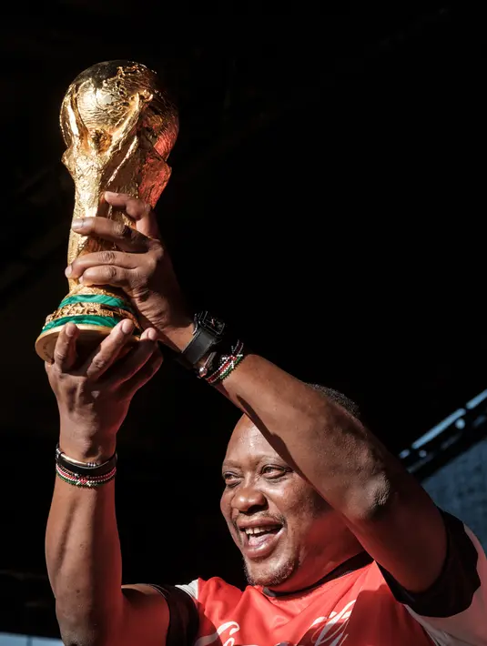 Presiden Kenya Uhuru Kenyatta menunjukkan Piala Dunia FIFA saat Tur Dunia di Gedung Negara, Nairobi (26/2). Ini adalah kali ketiga trofi emas 1 billion mendarat di Kenya. (AFP Photo/Yasuyoshi Chiba)