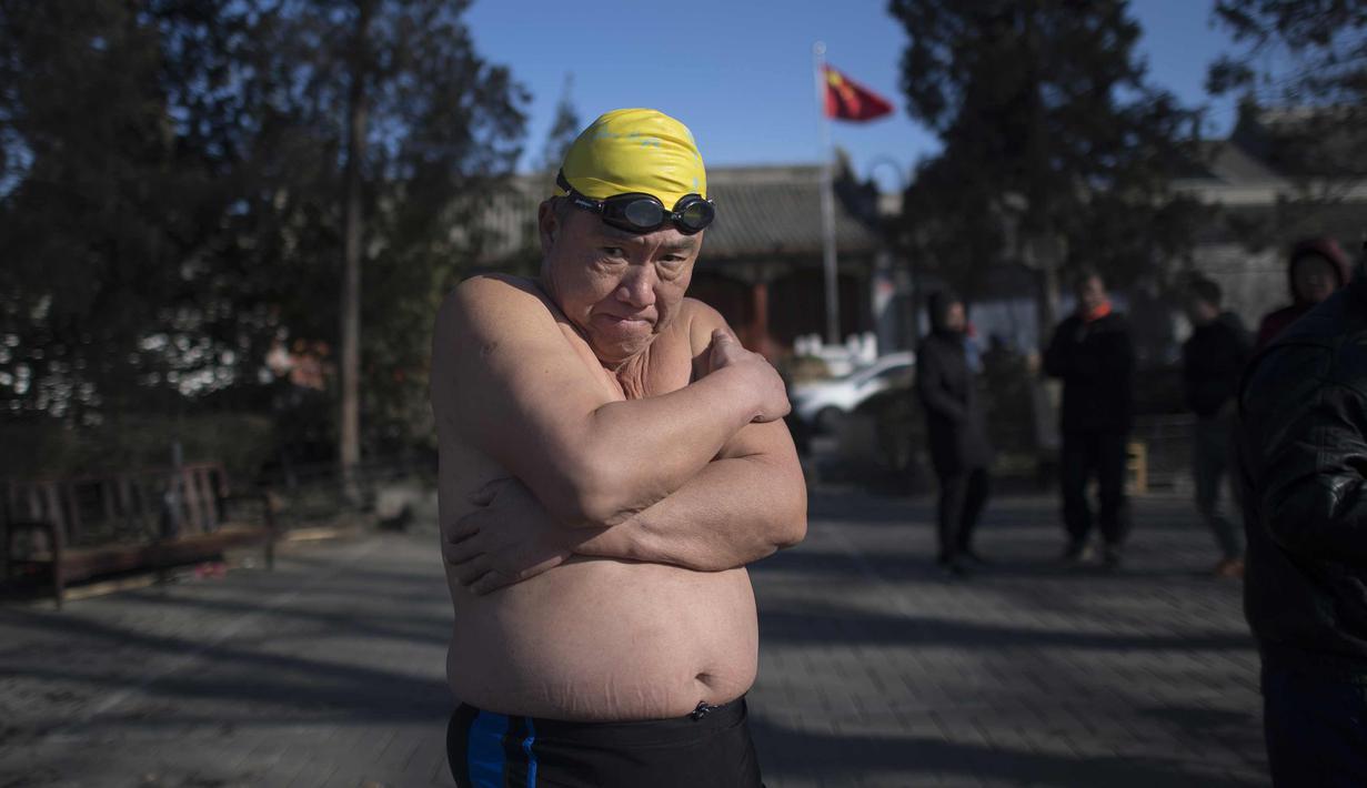Seorang pria melakukan pemanasan untuk berenang di danau Hou Hai yang beku di Beijing, China (24/1). (AFP Photo/Nicolas Asfouri)