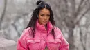 Rihanna menunjukkan baby bump-nya dengan mengenakan jaket merah muda cerah yang tidak dikancing di bagian bawah untuk memamerkan perutnya, yang dihiasi dengan salib emas dan permata. (Instagram/badgalriri).