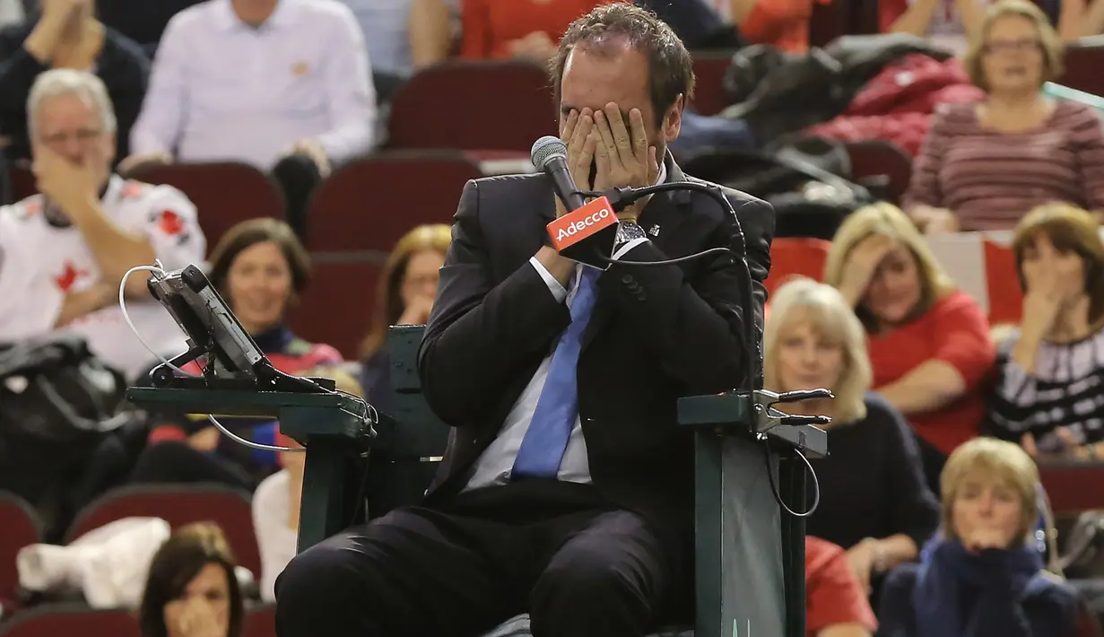 Wasit asal Prancis, Arnaud Gabas, menutupi wajahnya setelah terkena lemparan bola tenis saat petenis Kanada Denis Shapovalov melawan petenis Inggris Kyle Edmund pada putaran pertama Piala Davis di Ottawa, Kanada, Minggu (5/2). (Lars Hagberg/AFP)