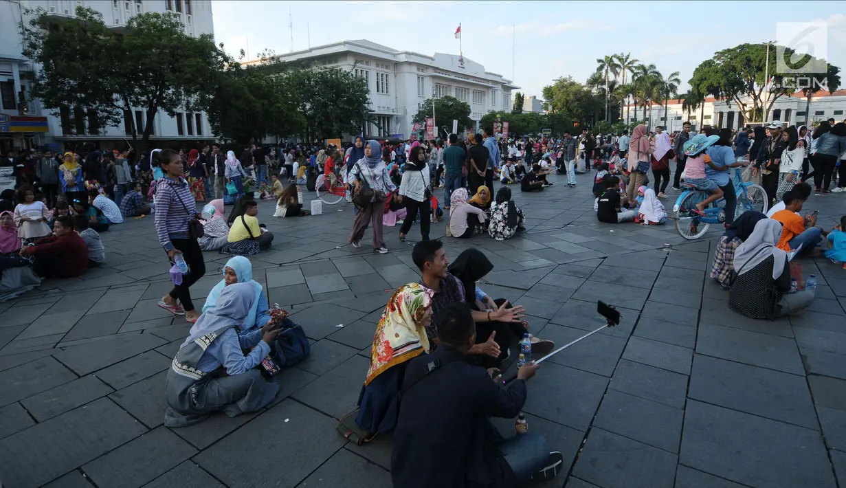 Warga duduk beristirahat di pelataran Museum Fatahillah, Jakarta, Selasa (19/6). Kemudahan transportasi dan biaya yang murah menjadikan kawasan ini sebagai lokasi favorit warga untuk menghabiskan waktu libur. (Liputan6.com/Helmi Fithriansyah)