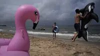 Seorang pria bermain dengan ban karet lumba-lumba di pantai Sijung Ho di Korea Utara (14/7/2019). Pantai Sijung Ho merupakan tujuan wisata populer bagi penduduk lokal dan asing. (AP Photo/Vincent Yu)