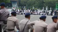 Massa aksi damai 4 November bersiap menggelar salat Jumat di Jalan Merdeka Barat, Jakarta, Jumat (4/11). Personel keamanan dari kepolisian pun disiagakan berbaris berhadapan dengan massa pendemo. (Liputan6.com/Faizal Fanani)