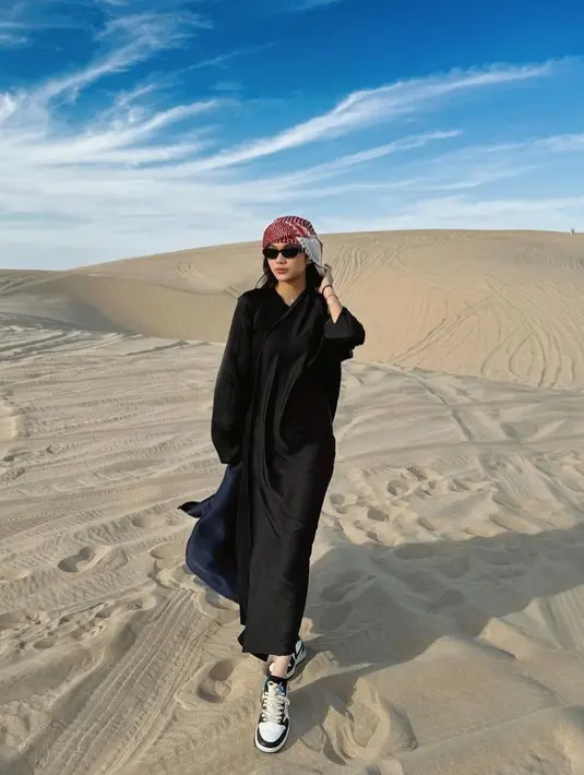 Ia memadukan dress hitam tersebut dengan sneakersnya.  [@azizahsalsha_]