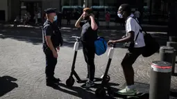 Polisi anti huru-hara memberi informasi tentang kewajiban penggunaan masker kepada warga di Marseille, Selasa (18/8/2020). Pemerintah Prancis mengirim polisi anti huru hara untuk membantu menegakkan peraturan penggunaan masker saat negara itu mencatat lonjakan kasus COVID-19. (AP Photo/Daniel Cole)