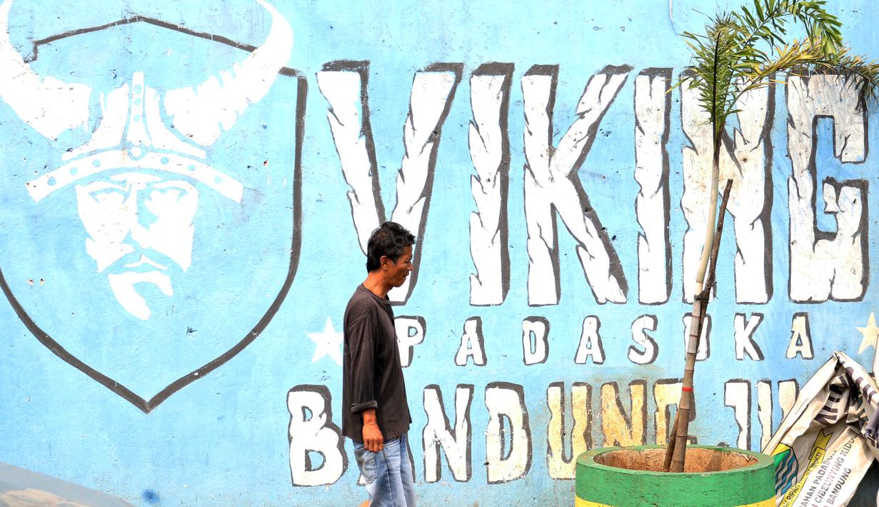 Seorang warga melintas dekat mural Viking di Bandung. (Bola.com/Nicklas Hanoatubun)