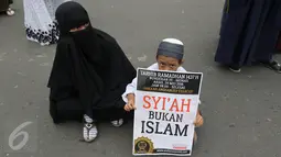 Seorang anak memegang poster saat mengikuti aksi Tarhib Ramadhan di Bundaran HI, Jakarta Pusat, Minggu (29/5). Aksi tersebut selain Tarhib Ramadhan mereka juga menolak ajaran syi'ah, Komunis dan kaum LGBT. (Liputan6.com/Herma Zakharia)