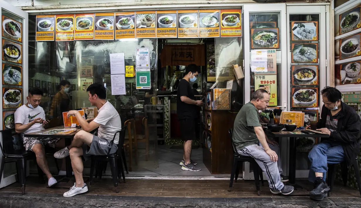 Pelanggan bersantap di sebuah restoran saat pemerintah mengumumkan pelonggaran pembatasan Covid-19 paling ketat, di Hong Kong, Kamis (14/4/2022). Pelonggaran tersebut akan memungkinkan salon kecantikan, bioskop, dan pusat kebugaran dibuka kembali mulai 21 April 2022 mendatang. (ISAAC LAWRENCE/AFP)