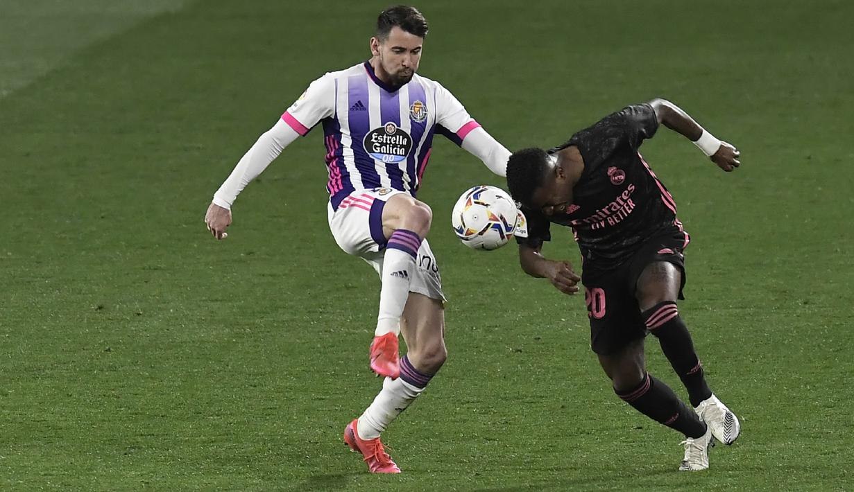 Pemain Real Valladolid, Luis Perez, berebut bola dengan pemain Real Madrid, Vinicius Junior, pada laga Liga Spanyol di Stadion Jose Zorrila, Minggu (21/2/2021). Real Madrid menang dengan skor 1-0. (AP/Alvaro Barrientos)