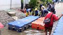 Petugas membuat jembatan apung saat banjir melanda Perumahan Periuk Damai, Tangerang, Banten, Selasa (23/2/2021). Adanya jembatan apung mempermudah warga saat melintasi banjir setinggi 2,5 meter di tempat tersebut. (Liputan6.com/Angga Yuniar)