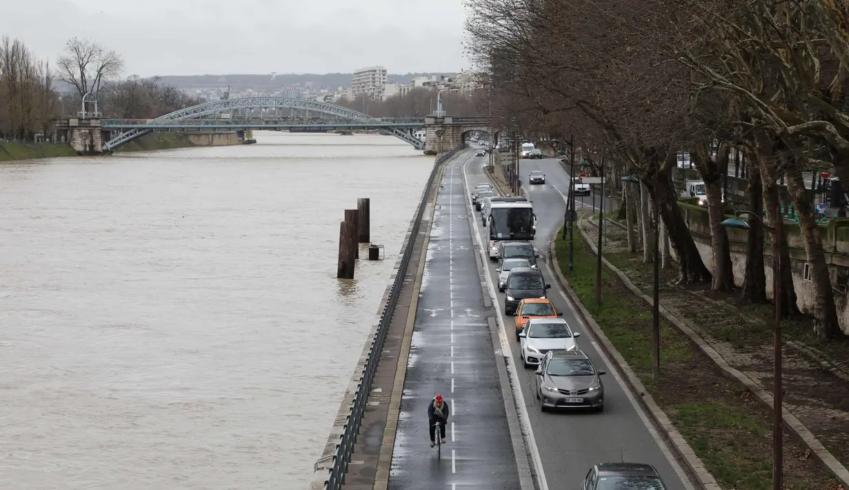Sejumlah kendaraan melintas di samping sungai Seine yang meluap, Paris, Prancis (5/1). Meluapnya air di sungai Seine akibat tidak mampu menampung debit air setelah hujan terjadi terus-menerus. (AFP Photo/Ludovic Marin)
