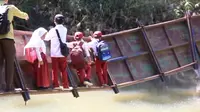 Siswa SD saat melewati jembatan rusak nyaris putus penghubung 2 kecamatan di Kabupaten Sukabumi (Liputan6.com/Fira Syahrin).