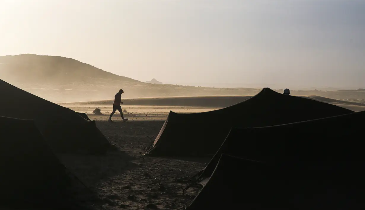 Seorang peserta berjalan di antara tenda sebelum memulai kembali mengikuti kompetisi Marathon des Sables ke-33 di gurun Sahara, Maroko (13/4). (AP Photo / Mosa'ab Elshamy)