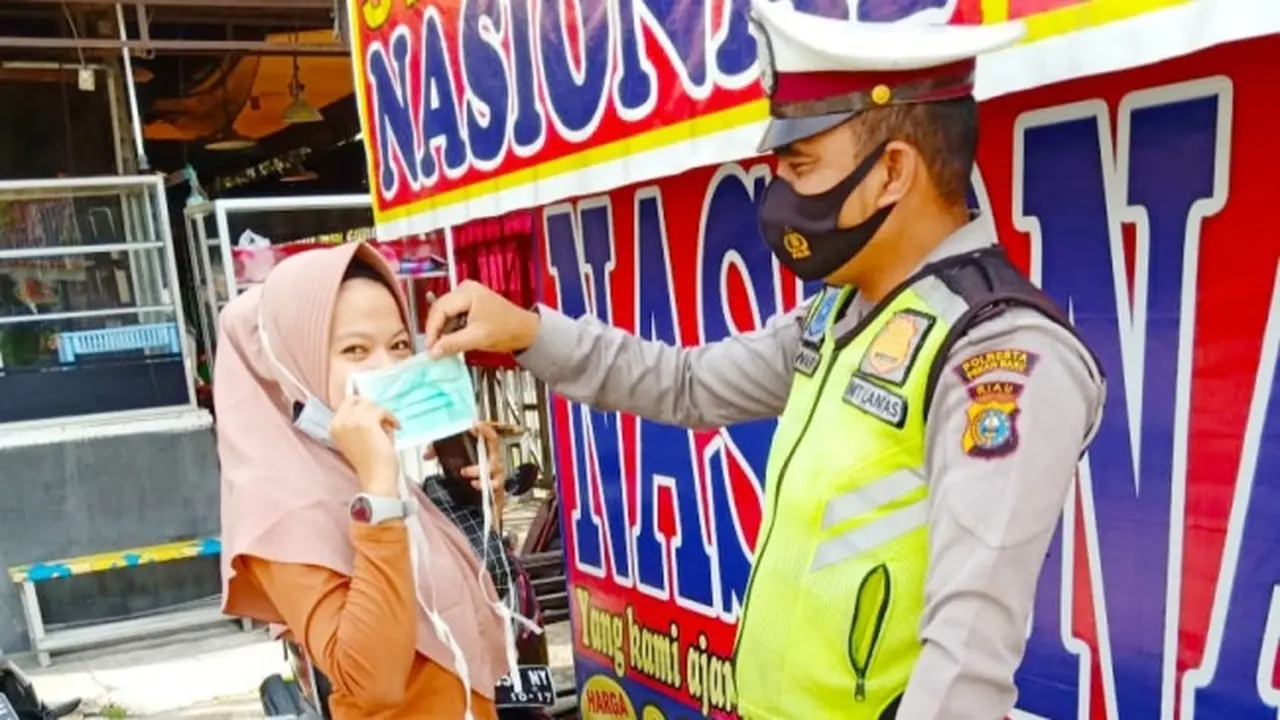 Personel Direktorat Lalu Lintas Polda Riau bagikan masker kepada penggendara saat Operasi Zebra.