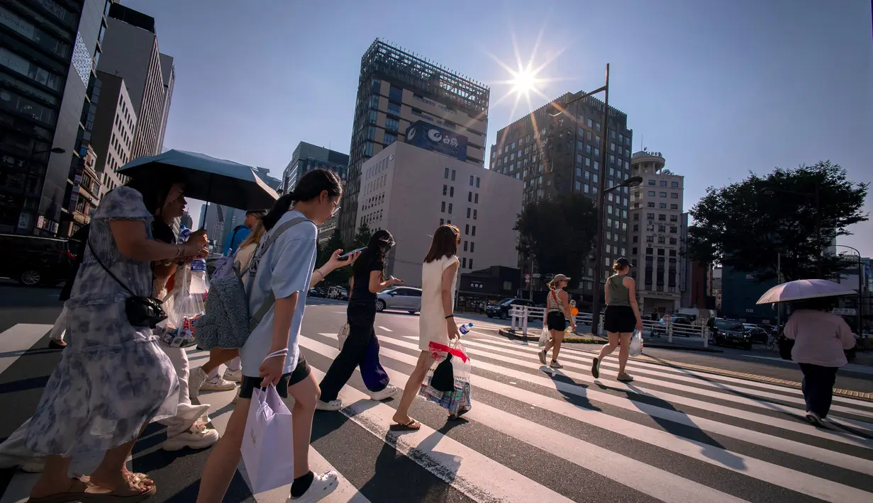 Jepang menjadi salah satu negara yang mengalami gelombang panas ekstrem, bahkan suhu mencapai 41,2 derajat celcius di Hyogo, 30 Juli 2025 lalu. Tampak dalam foto, orang-orang menyeberang jalan di Tokyo pada 4 Agustus 2025. (Kazuhiro NOGI/AFP)