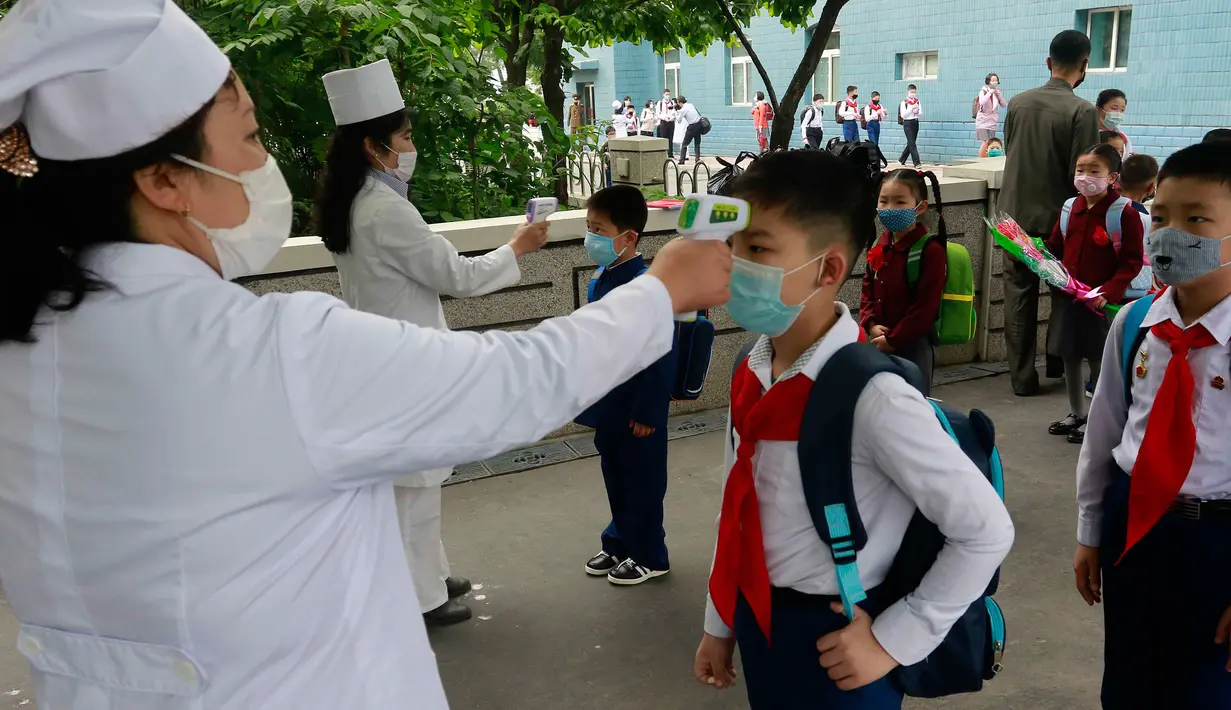 Siswa sekolah dasar Kim Song Ju diperiksa suhu tubuhnya sebelum memasuki sekolah di Pyongyang, Korea Utara, Rabu (3/6/2020). Korea Utara membuka kembali sekolah - sekolah di negara itu pada bulan ini setelah sebelumnya meliburkan karena kekhawatiran penyebaran virus corona. (AP/Jon Chol Jin)