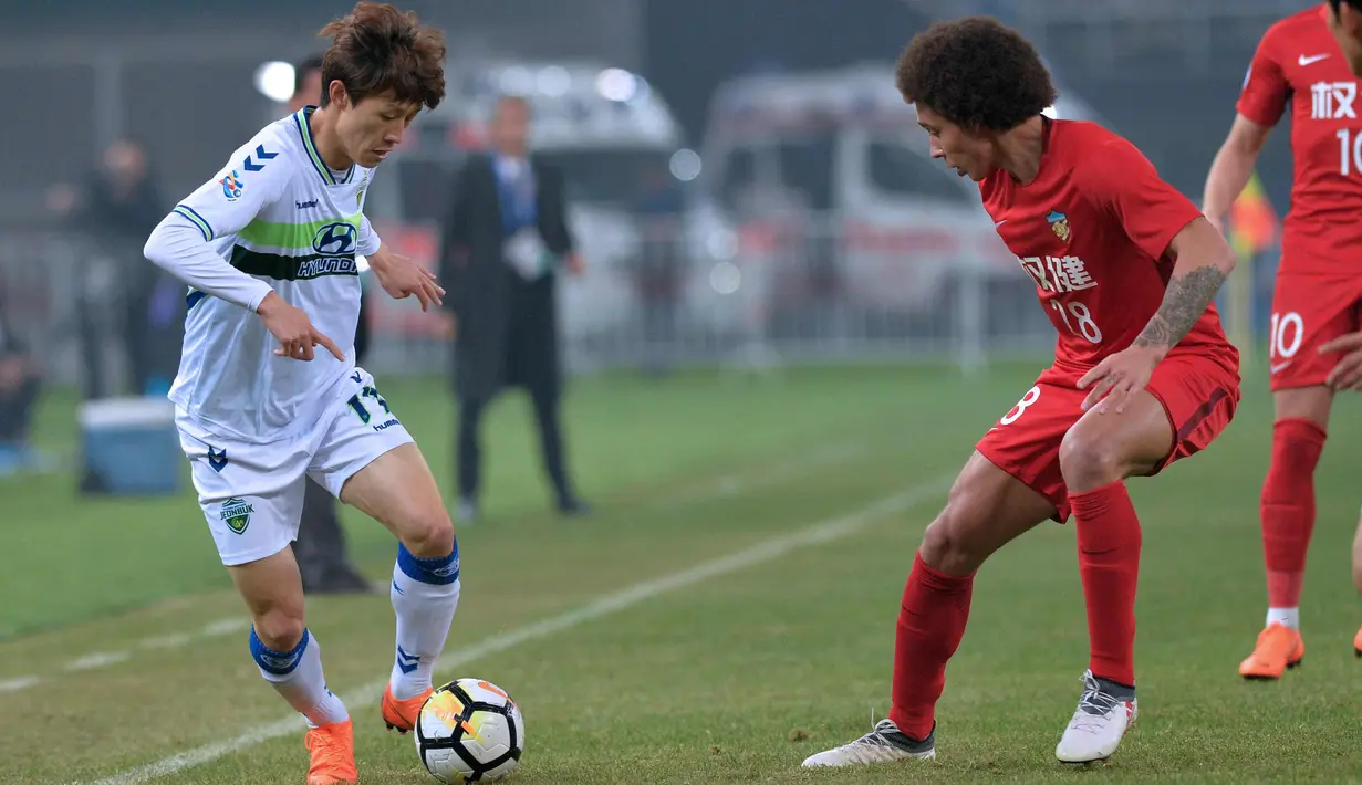 Pemain Jeonbuk Hyundai, Lee Jae-sung (kiri) berusaha melewati pemain Tianjin Quanjian, Axel Witsel saat bertanding pada Liga Champions AFC di Tianjin (14/3).  Tianjin menang 4-2 atas tim Korea tersebut. (AFP Photo)