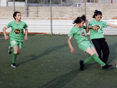 Dua pesepak bola putri klub Beit Umar Palestina berebut bola saat mengikuti sesi latihan di sebuah lapangan di Kota Hebron. (AFP/Hazem Bader)