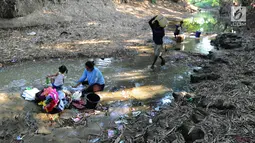 Warga mencuci pakaian dengan air dari lubang pada aliran Sungai Cihoe yang digunakan untuk memenuhi kebutuhan sehari-hari di Ridogalih, Cibarusah, Bekasi, Minggu (7/7/2019). Sudah lebih dari dua bulan, warga memanfaatkan sisa aliran sungai yang kotor akibat musim kemarau. (merdeka.com/Arie Basuki)
