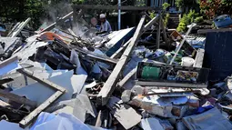 Seorang pria menyelamatkan barang berharga dari puing rumah yang rusak di Menggala, Lombok Utara, Rabu (8/8). Warga terdampak gempa Lombok mulai mengamankan barang berharga miliknya karena kuatir dijarah pihak tidak bertanggung jawab. (AFP/ADEK BERRY)