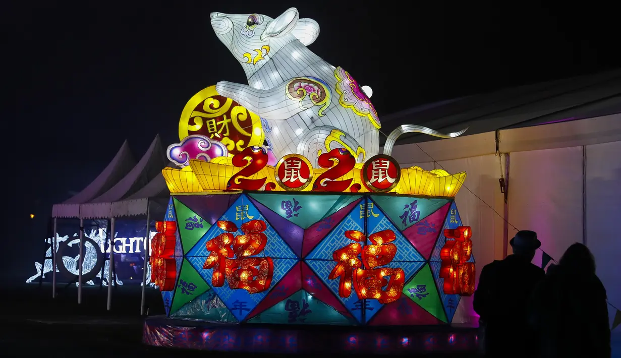 Para pengunjung melihat instalasi cahaya berbentuk hiasan imlek tahun tikus di Chiswick House and Gardens dalam acara resmi penyalaan Festival Lightopia (sesi pemotretan) di London, Inggris (21/1/2020). Lightopia dibuka untuk umum dari 22 Januari hingga 1 Maret. (Xinhua/Han Yan)