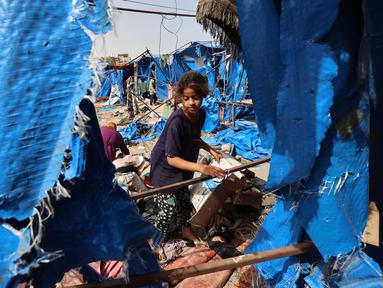 Seorang anak memeriksa kerusakan tenda-tenda untuk warga Gaza yang mengungsi di luar rumah sakit Martir Al-Aqsa, Deir el-Balah, Jalur Gaza Tengah, setelah serangan udara Israel semalam yang dilaporkan menghantam, pada 17 Mei 2025. (Eyad BABA/AFP)