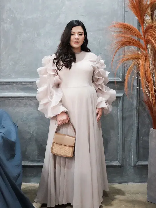 <p>Eriska Rein tampil anggun deengan busana rancangan Barli Asmara. Maxi Dress dengan aksen ruffle di bagian lengan membuatnya terlihat cantik meski tampil dengan nuansa nude. (instagram/eriskarein)</p>