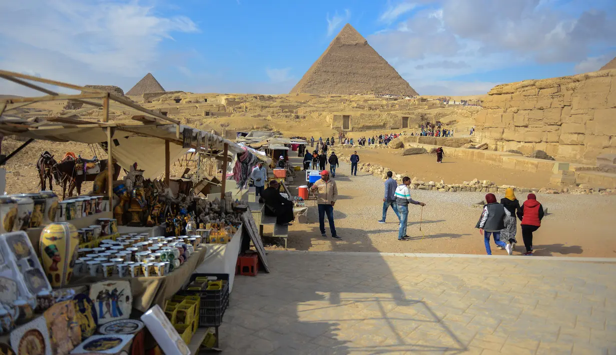 Sejumlah pedagang menjajakan dagangannya di dekat kompleks Piramida Giza di pinggiran Ibukota Kairo, Mesir (6/12). Piramida-piramida yang ditemukan disini adalah kategori terbesar dibandingkan dengan piramida yang ada di bumi.(AFP Photo/Mohamed El-Shahed)