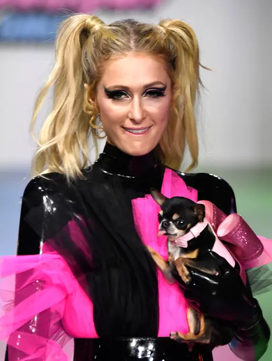 Paris Hilton membawa anjing saat tampil dalam Christian Cowan x The Powerpuff Girls Fashion Show, Los Angeles, AS, Jumat (8/3). Paris Hilton memamerkan gaun tulle merah muda bercampur hitam cerah. (Frazer Harrison/Getty Images North America/AFP)